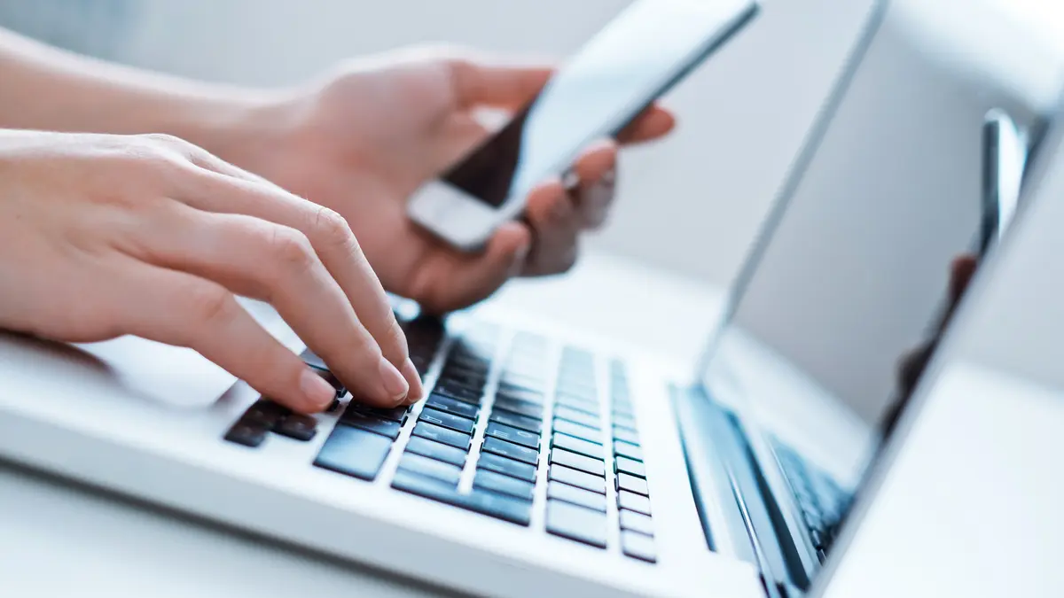 Nahaufnahme von jemandem, der Laptop und Smartphone nutzt