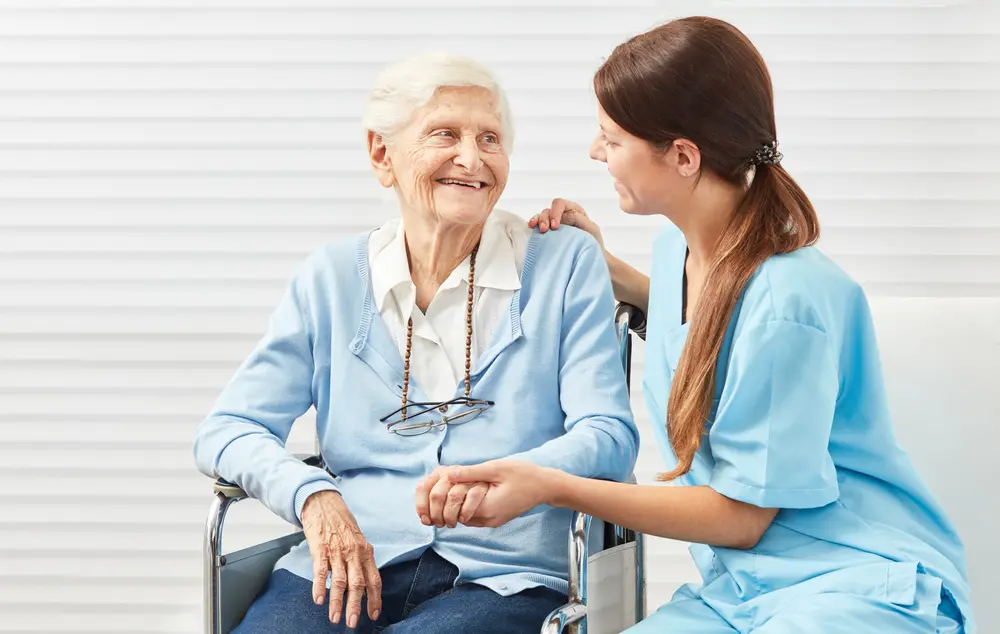Pflegerin kümmert sich um Seniorin im Rollstuhl