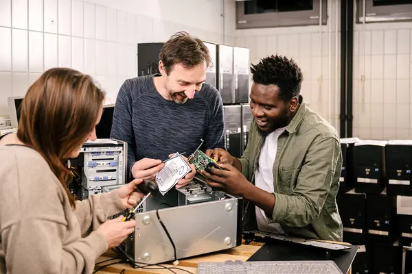 Drei Personen reparieren einen Computer.