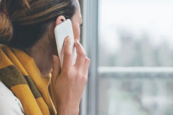 Eine Frau telefoniert und blickt aus einem Fenster.