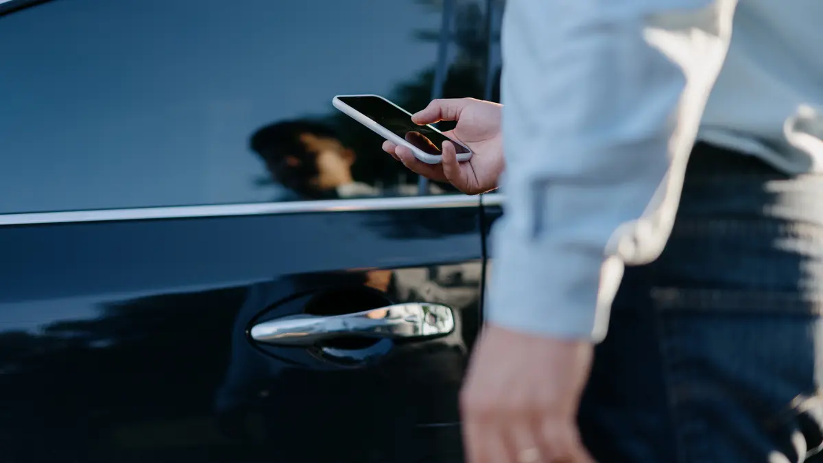 Mann beim Öffnen der Tür eines Autos mit seinem Smartphone