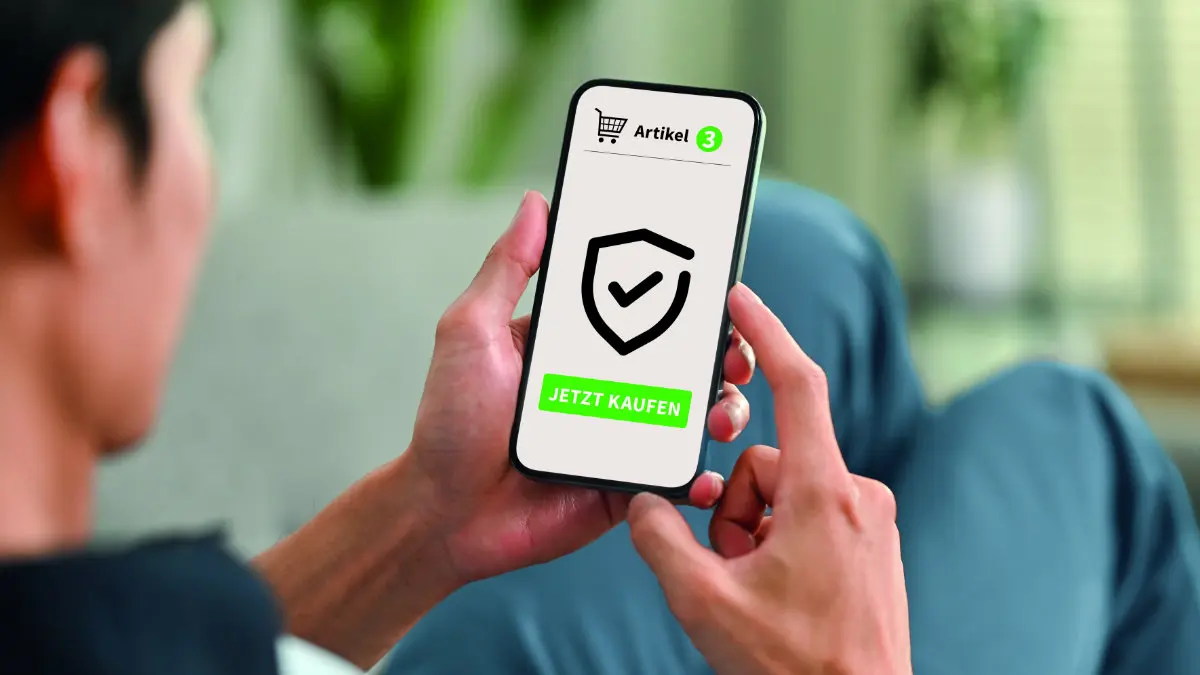 Ein Mann hält auf einem Sofa liegend ein Smartphone in der Hand, auf dessen Display ein Einkaufswagen und ein Schild zu sehen sind sowie die Aufschrift: "3 Artikel jetzt kaufen"