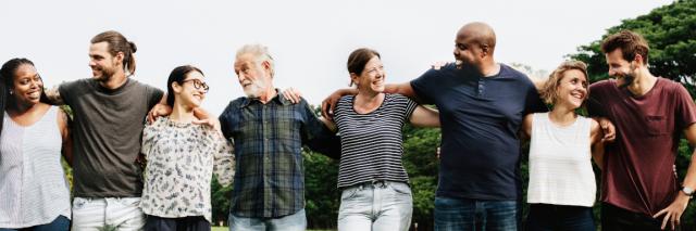 Eine diverse Menschengruppe bildet eine Kette der Umarmung und sieht sich dabei paarweise in die Augen