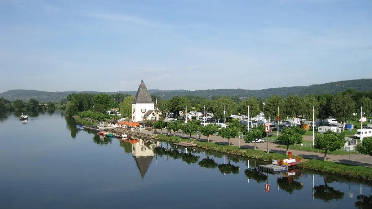 Links im Bild fließt ein Fluss; rechts im Bild ist eine Uferpromenade mit einem Turm.
