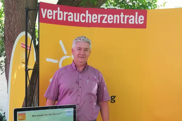 ein mann vor dem Plakat der Verbraucherzentrale