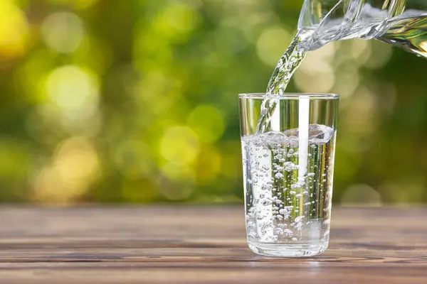 Wasser wird aus einer Karaffe in ein Glas eingeschenkt