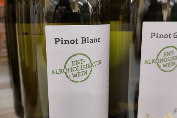 Zwei Flaschen Pinot Blanc mit der Aufschrift "Entalkoholisierter Wein" stehen in einem Regal.