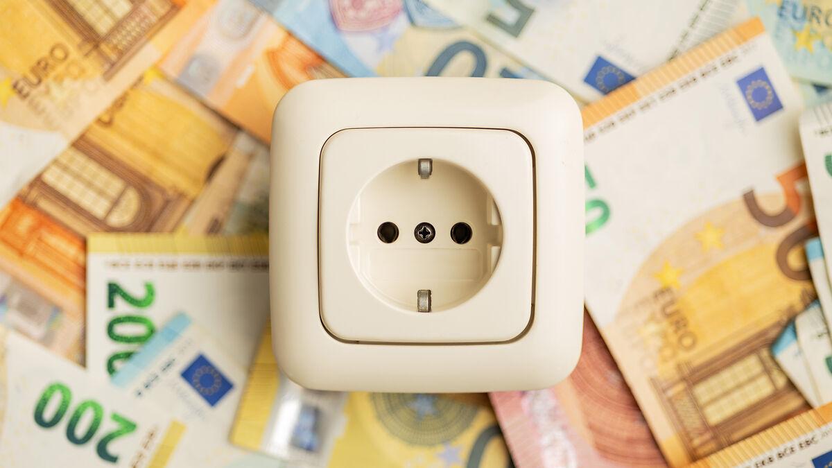 Steckdose, im Hintergrund liegen Geldscheine