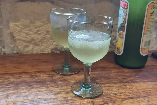 Zwei Weingläser mit Federweißer stehen neben einer Federweißer-Flasche.