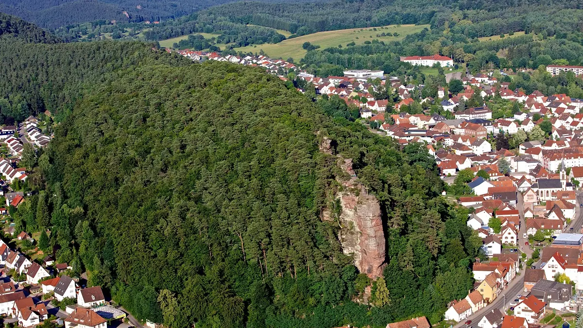 Ein Wald mit einem Felsen und drumherum eine Kleinstadt.