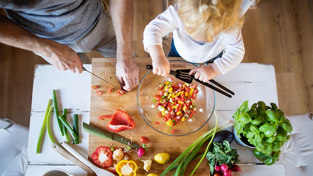 Vater und Kind schneiden gemeinsam Gemüse
