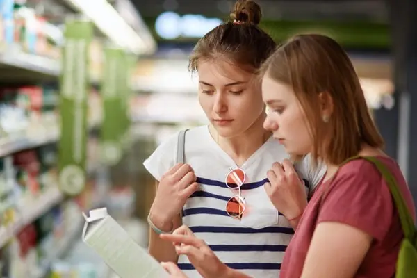 zwei junge Frauen schauen eine Verpackung im Lebensmittelladen an