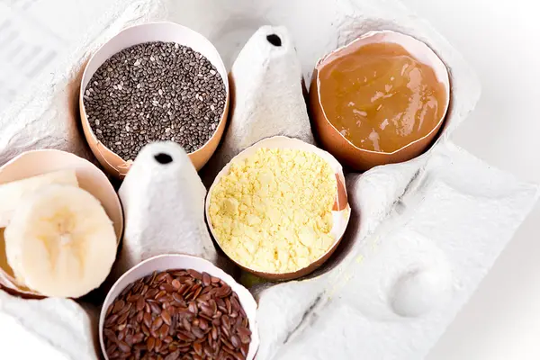 Vegane Ei-Ersatzprodukte in Eierschalen und einem Pappbehälter angerichtet