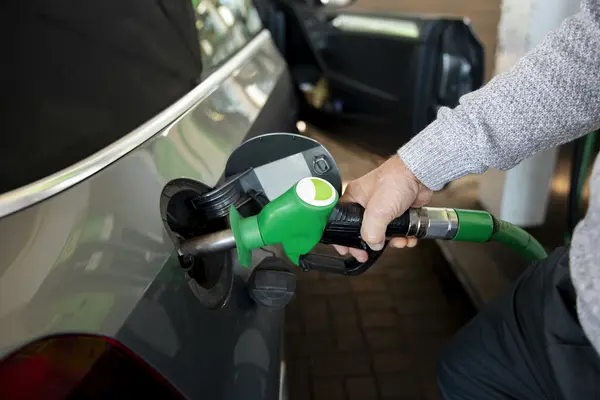 Eine Hand hält an einer Tankstelle eine Zapfpistole in die Tanköffnung