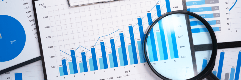 Eine Lupe wird über Bilanzunterlagen mit Diagrammen gelegt