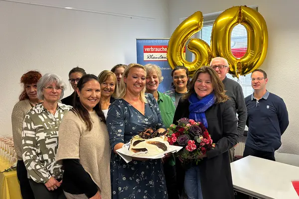 Eine Gruppe aus fröhlichen Menschen, die einen Kuchen in die Kamera halten