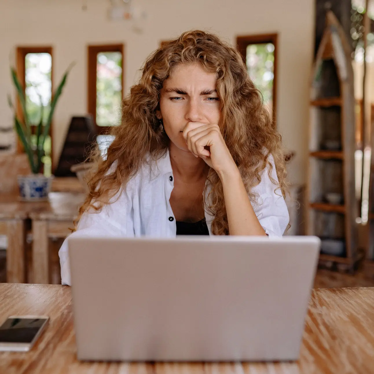 Ein Frau sitzt mit skeptischem Gesichtsausdruck vor einem Laptop.