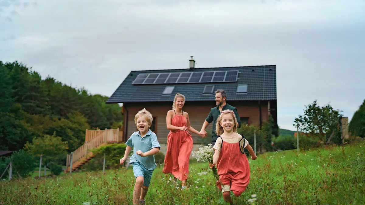 Familie auf einer Wiese vor Haus mit Photovoltaikanlage