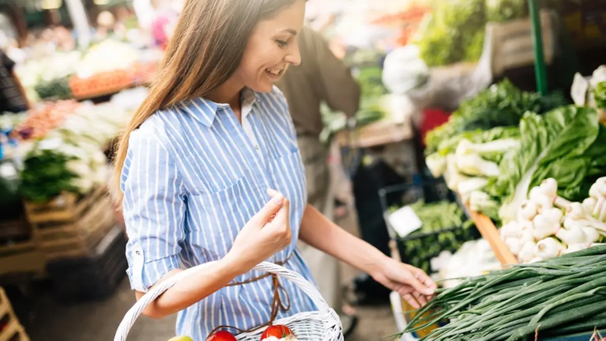 Eine Frau kauft auf einem Wochenmarkt in ihrer Region ein.
