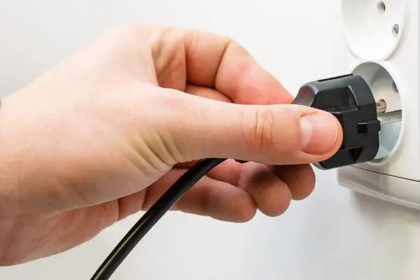 Hand hält Stecker an eine Steckdose