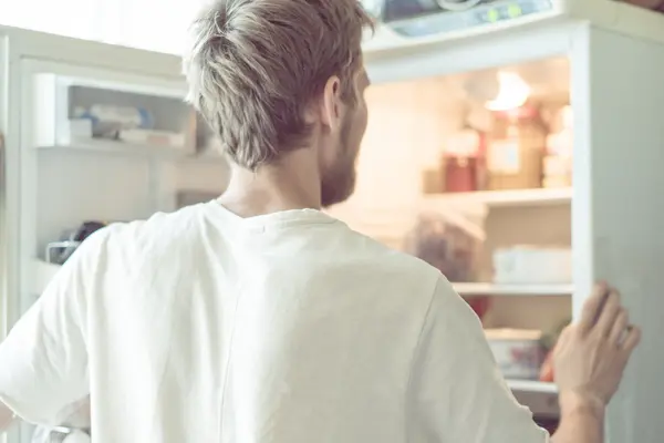 Ein Mann schaut in seinen Kühlschrank