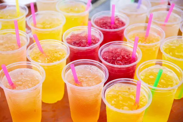 Mehrere Becher mit gelbem, orangefarbenem und rotem Slush Ice stehen nebeneinander.