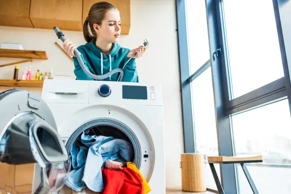 Frau hinter kaputter Waschmaschine