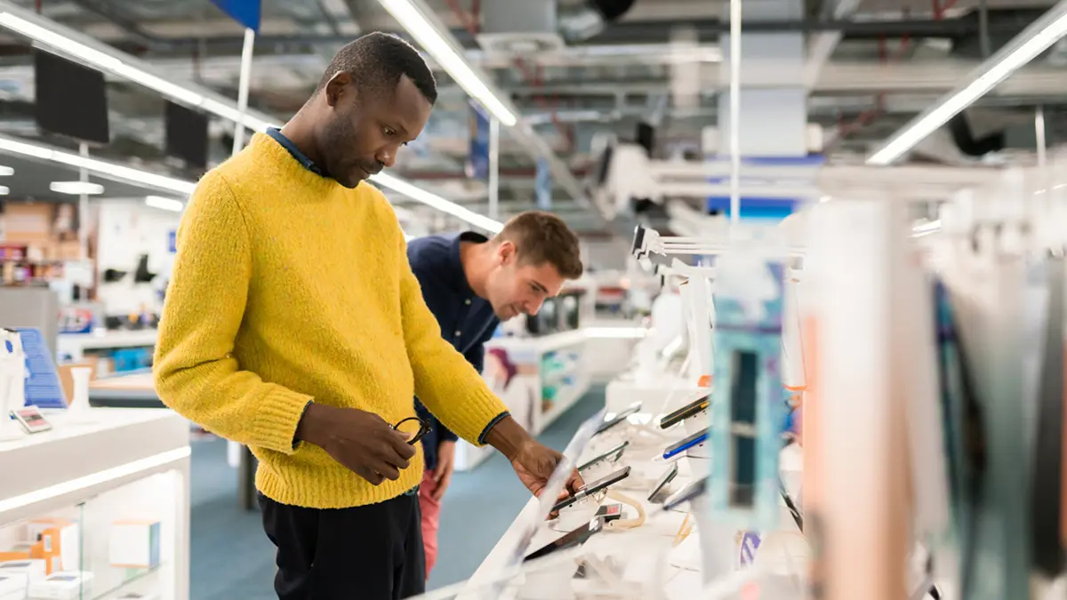 Zwei Männer begutachten Smartphones in einem Elektronikfachmarkt.