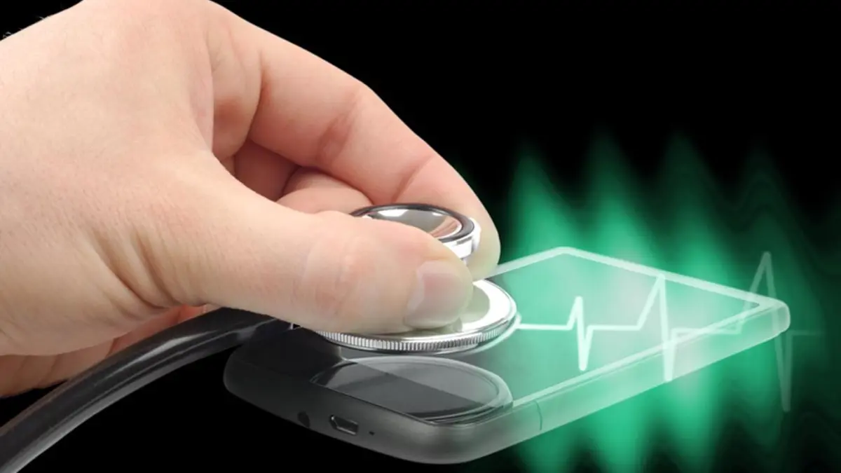 Hand hält Stethoskop auf Smartphone-Display, dazu eine Herzstromkurve