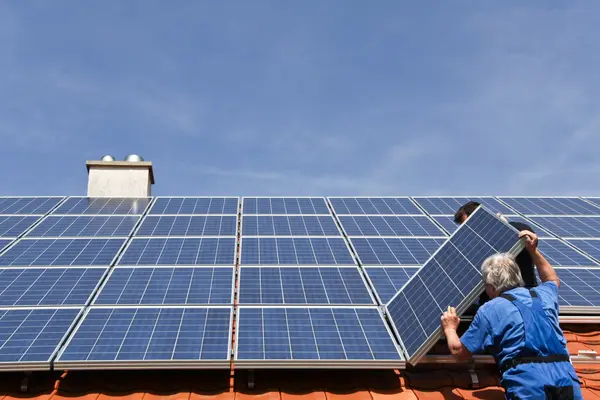 Eine PV-Anlage wird auf einem Dach von Monteuren installiert
