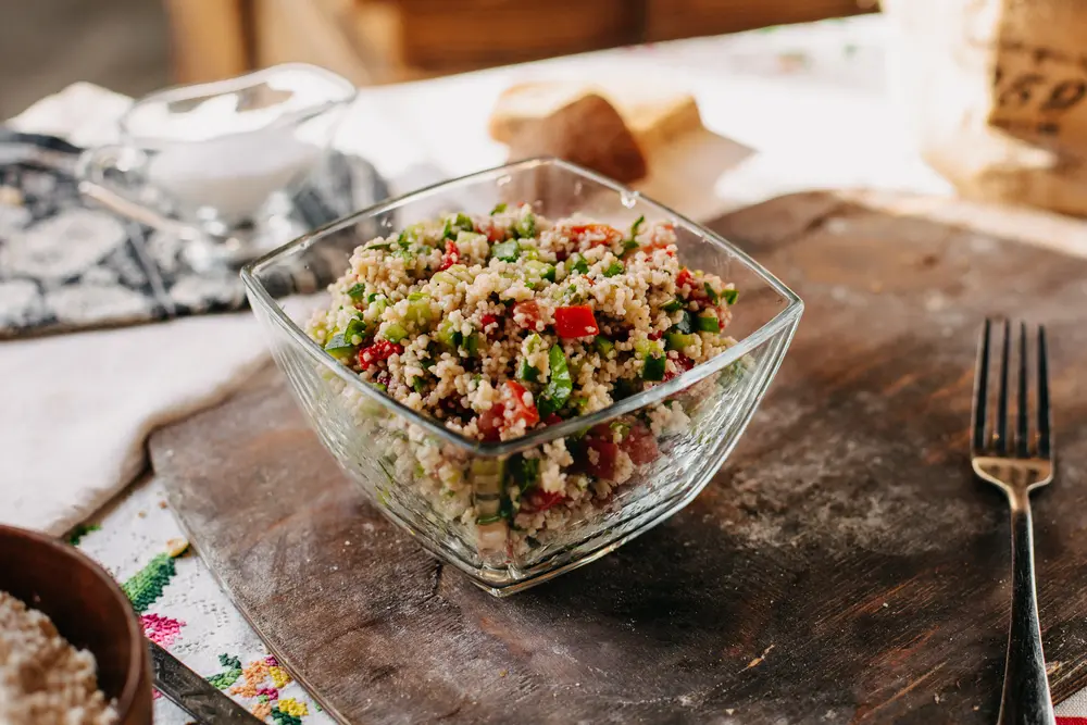 Eine Glasschale mit Couscous-Salat mit geschnittenem Gemüse 