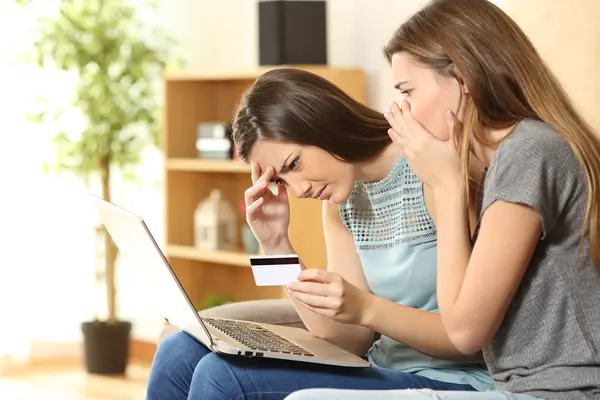 Zwei junge Frauen am Laptop schauen geschockt.