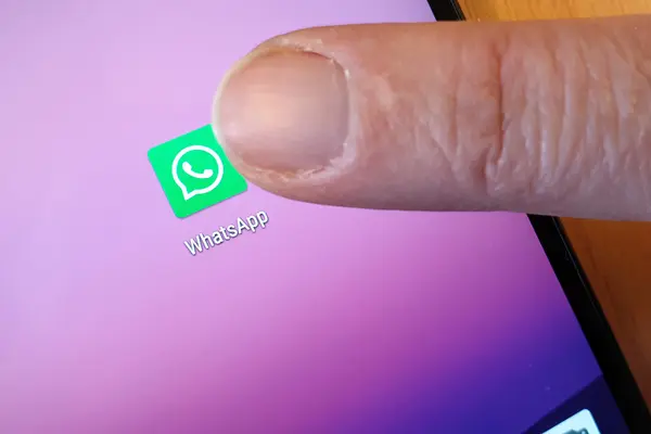 Ein Finger tippt aufs WhatsApp-Logo auf einem Smartphone-Display