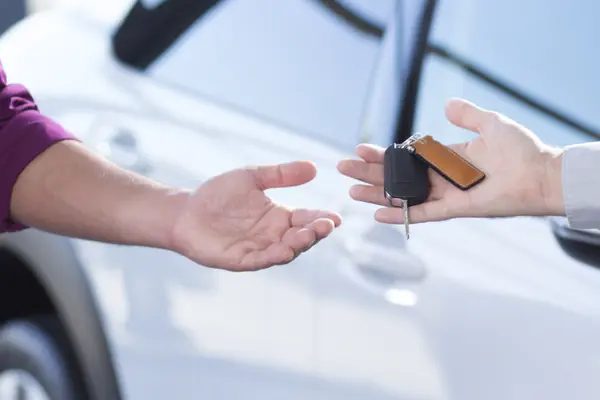 In der Nahaufnahme von zwei Händen übergibt ein Mann einer Frau einen Autoschlüssel