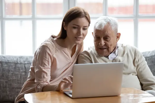 Ein Vater und seine erwachsene Tochter sitzen zusammen vor einem Laptop.
