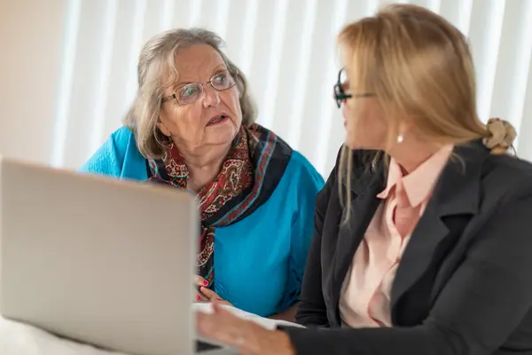 Zwei Frauen sprechen miteinander vor einem Laptop.