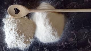 Instantmehl auf einer Arbeitsfläche, daneben liegt ein Holzkochlöffel