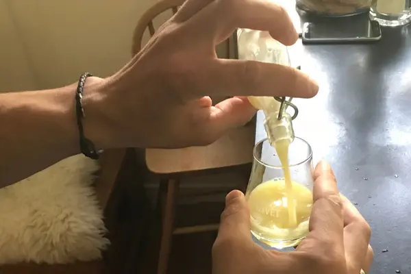 Ingwershot wird aus einer kleinen Flasche in ein Glas gefüllt