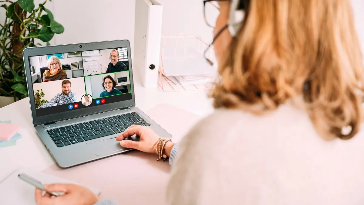 Frau vor Laptop spricht in einer Videokonferenz.