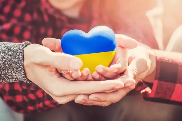 Hände halten ein Herz in den ukrainischen Farben blau und gelb
