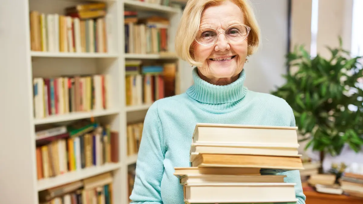 Rentnerin mit einem Stapel Bücher im Arm