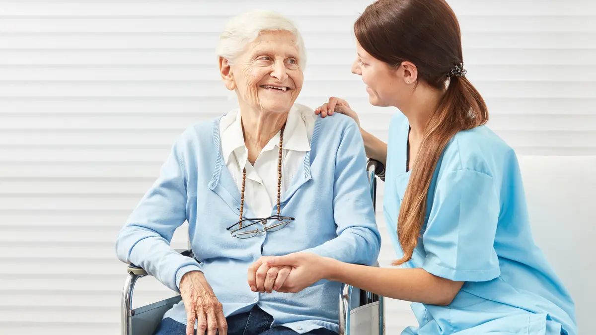 Pflegerin kümmert sich um Seniorin im Rollstuhl