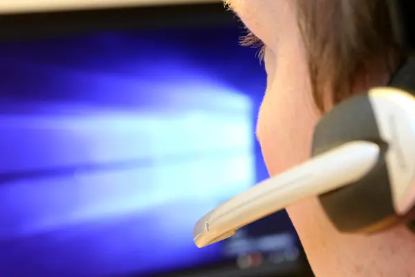 Mann mit Headset vor PC-Bildschirm