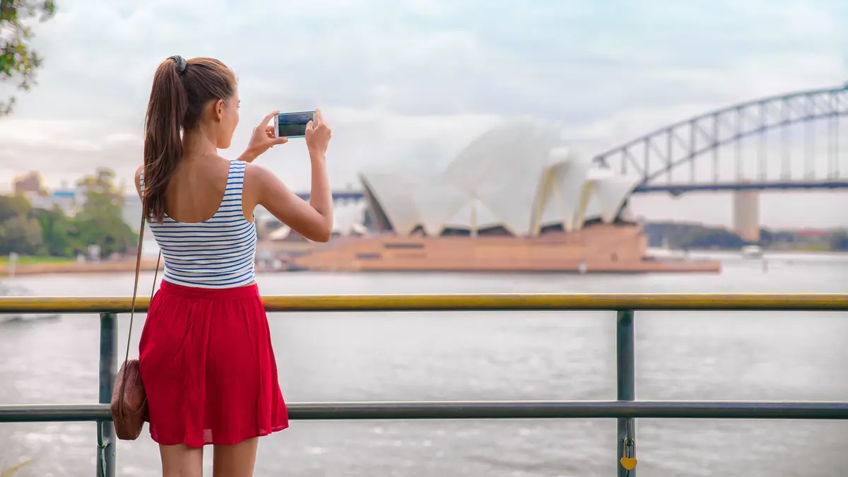 Junge Frau fotografiert Habour Bridge in Sydney.