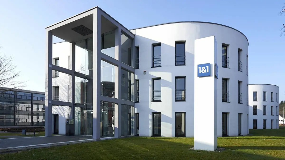 Firmenzentrale der 1&1 Telecom GmbH in Montabaur: Zwei weiße dreistöckige Gebäude und eine weiße Säule mit dem Logo 1&1, weiße Schrift auf blauem Quadrat