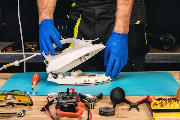Handwerker beim Reparieren eines Bügeleisens