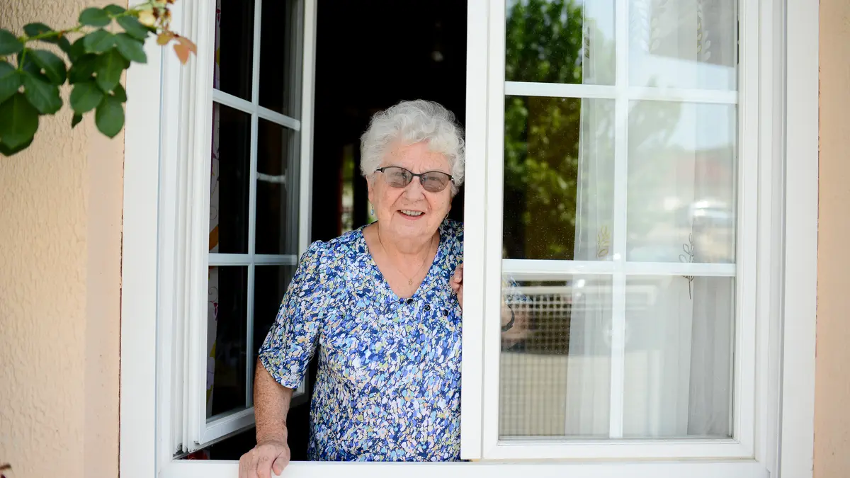 Seniorin steht am Fenster
