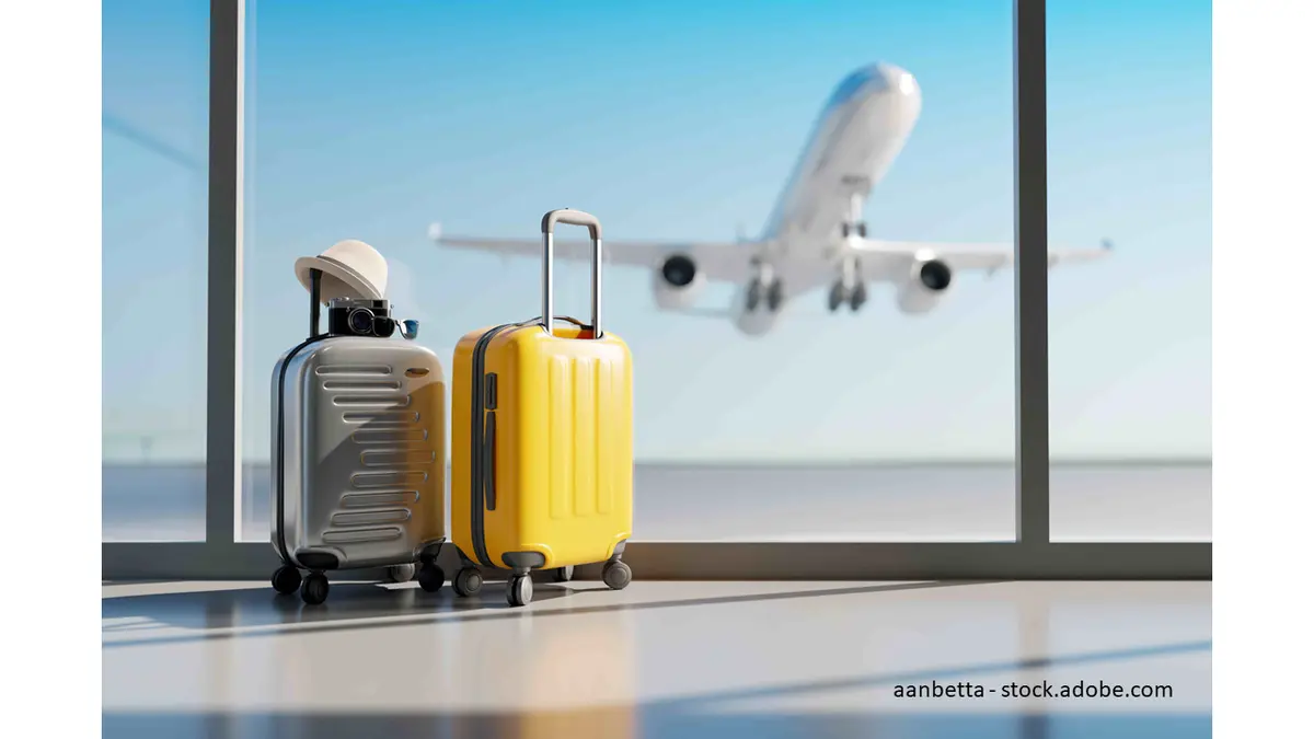 Koffer stehen alleine am Flughafen. Flieger hebt im Hintergrund  ab.