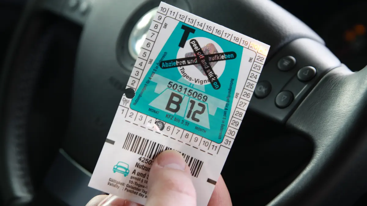 Mensch hält Vignette für Österreichische Autobahn in der Hand
