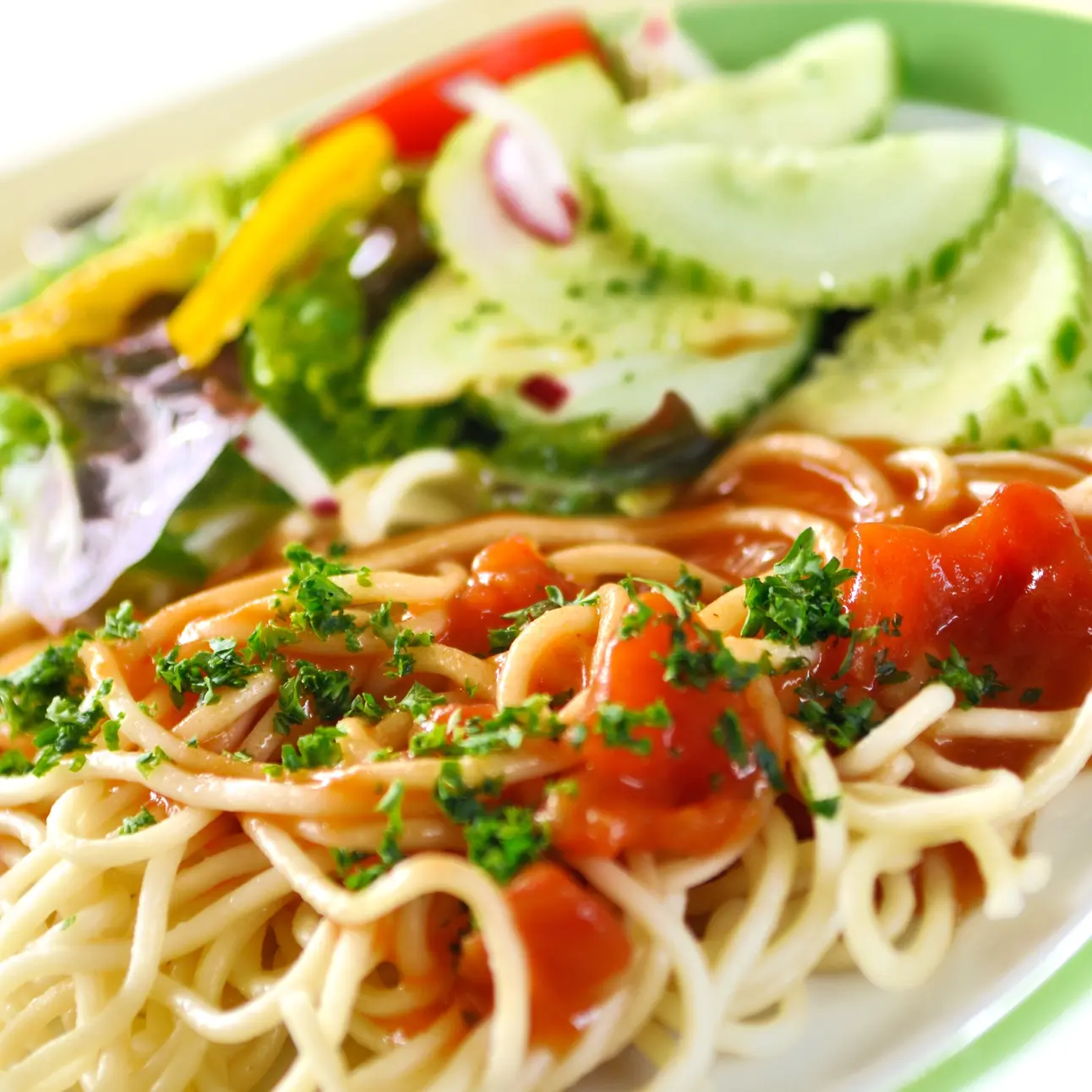 Spaghetti mit Tomatensauce und Salat auf einem Teller.